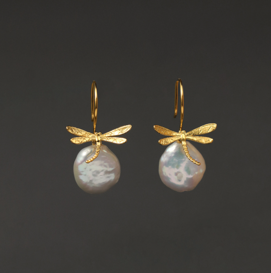 A pair of gold vermeil dragonfly earrings with pearl accents displayed against a black background.
