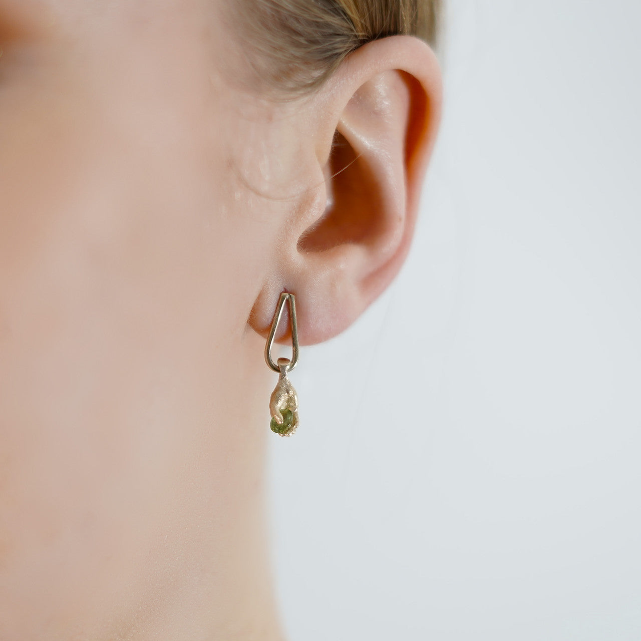 Fraser_Hamilton_handmade_jewellery_earrings_14K_yellow_gold_hands_dropping_dangling_green_sapphires_holding_sculptural_jewellery