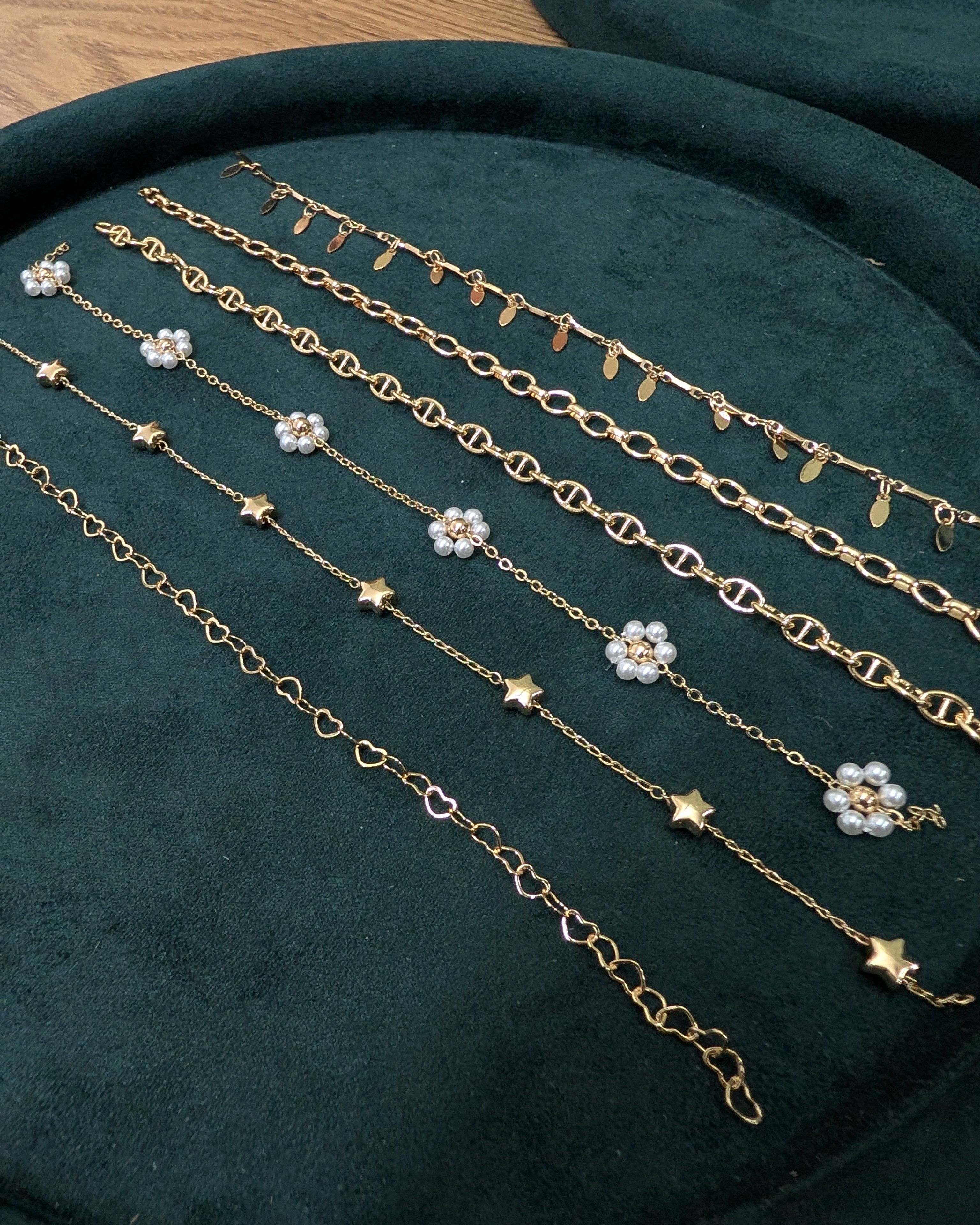 Gold necklaces with floral and star designs on a green velvet surface