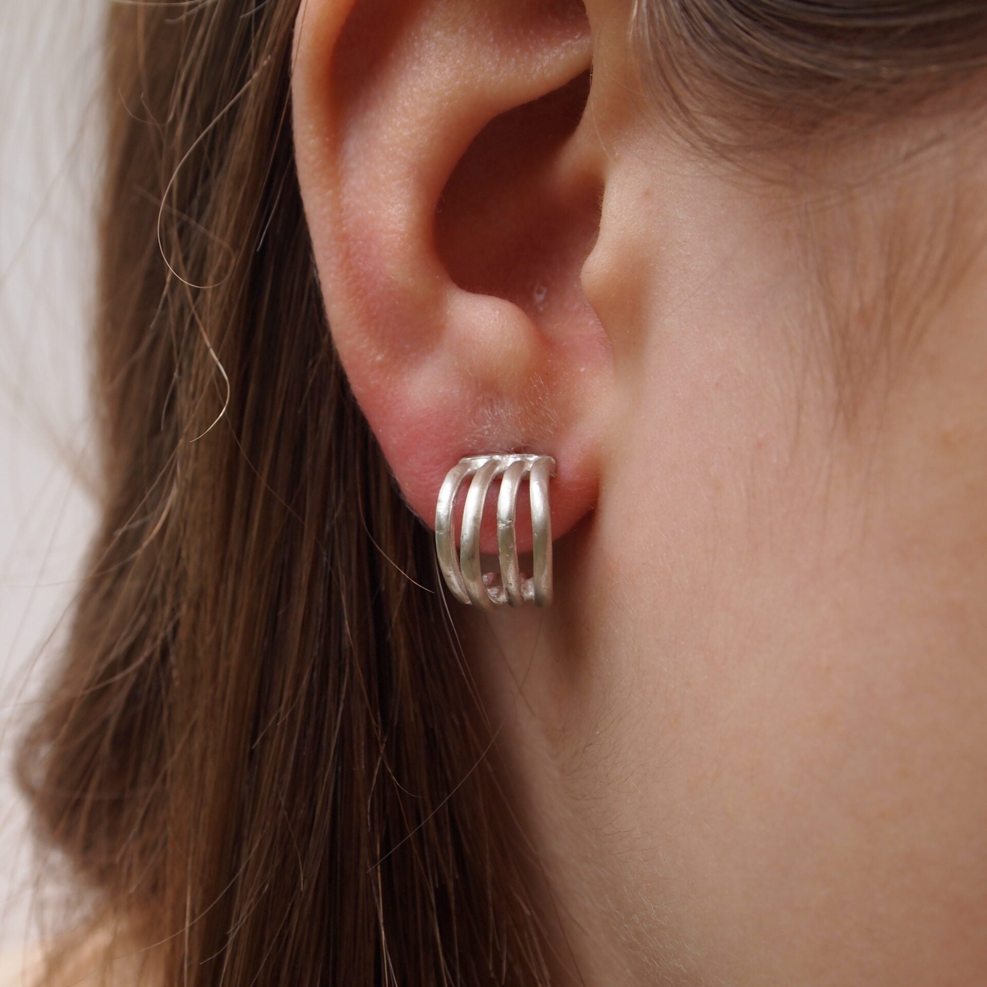 Close-up image of a person wearing sterling silver curved line stud earrings.