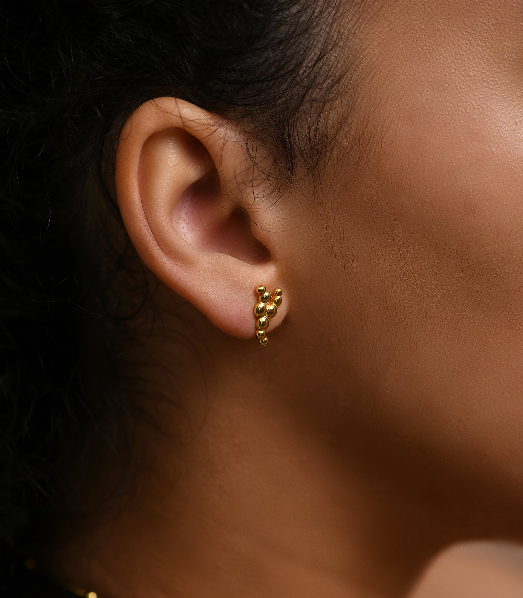 a close up photo of a female model wearing a gold plated silver stud earrings which is reminiscent of bubbles
