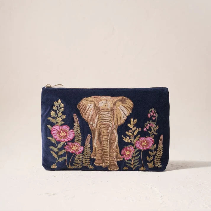 A navy blue velvet zip pouch featuring an embroidered elephant and pink flowers in gold and pink thread, set against a plain beige background.
