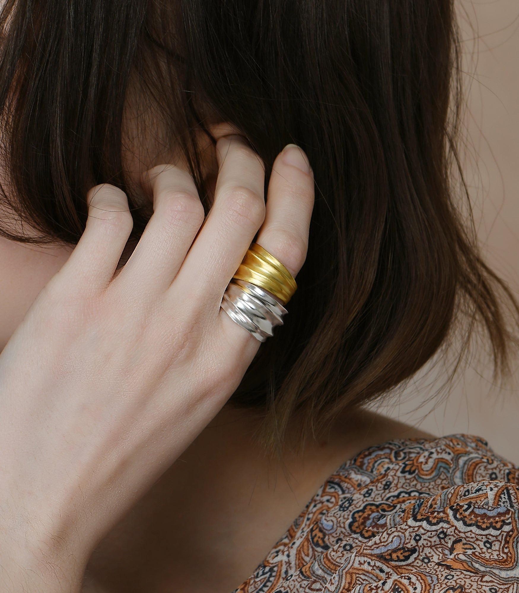 A gold vermeil ring and a sterling silver ring. Both have the same design featuring a wide band with smooth valleys and ridges.