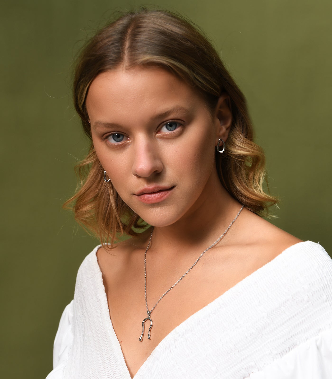 A model wears a pair of sterling silver, oval hoop drop earrings.